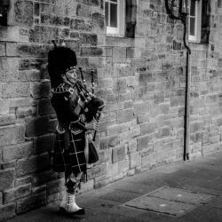 Person Using Bagpipes Near Wall in Grayscale Photography · Free