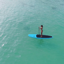 Aerial drone bird’s eye view of man exercising sup paddle board in